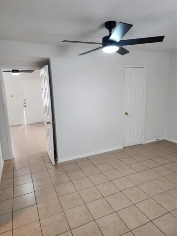 a view of an empty room and chandelier fan
