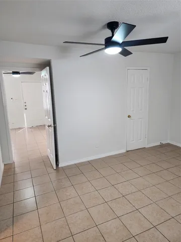 a view of an empty room and chandelier fan