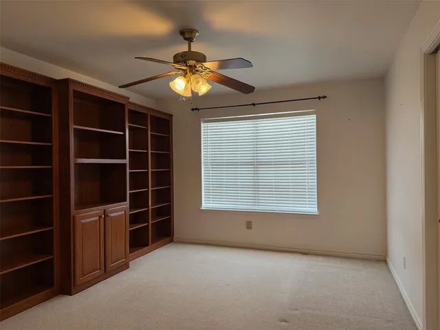a view of an empty room with a window and a kitchen