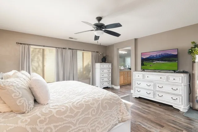 a bedroom with a bed a dresser and a flat screen tv
