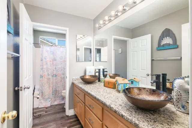 a bathroom with a granite countertop sink a mirror a vanity and shower