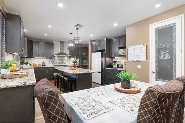 a kitchen with stainless steel appliances kitchen island granite countertop a refrigerator a stove a sink dishwasher with a dining table and chairs