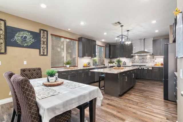 a kitchen with a dining table chairs stainless steel appliances and cabinets