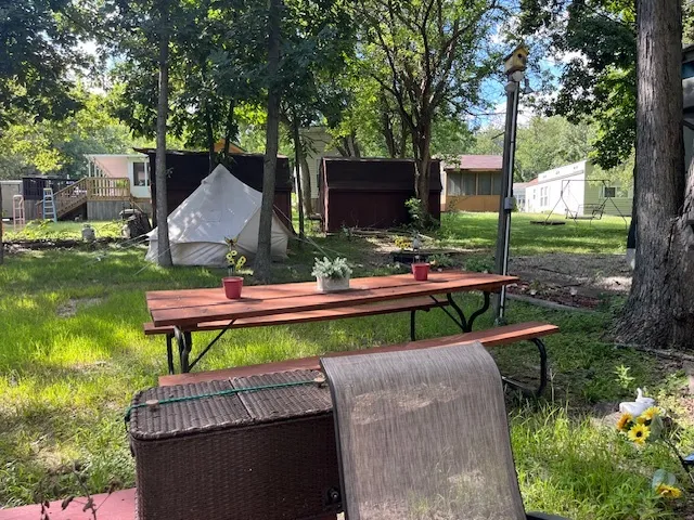 a view of a backyard with table and chairs potted plants and large tree
