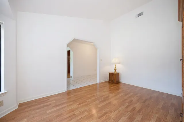a view of an empty room with window and wooden floor