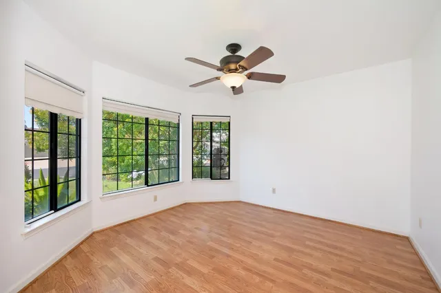 a view of an empty room with a window and wooden floor