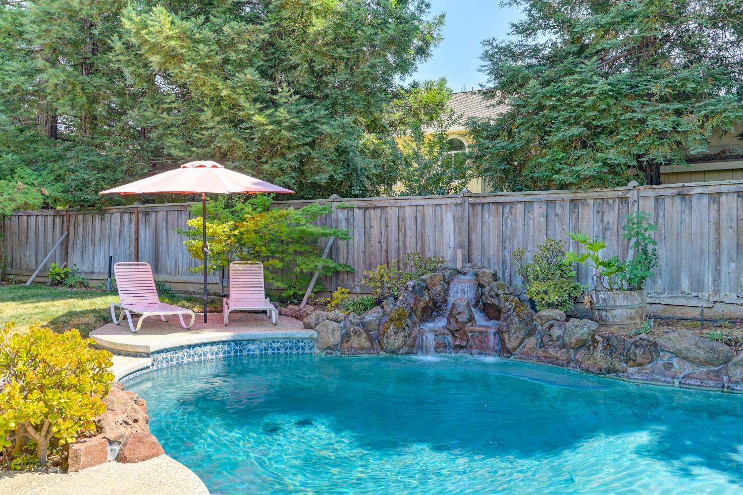 5408 East Brook Way Elk Grove, CA 95758 - Photo 4 of 53 a view of a backyard with table and chairs under an umbrella with wooden fence