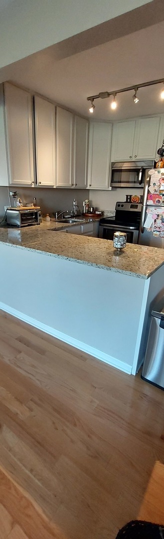 5854 Forest View Road, Unit E Lisle, IL 60532 - Photo 9 of 18 a view of a kitchen with an empty space and wooden floor