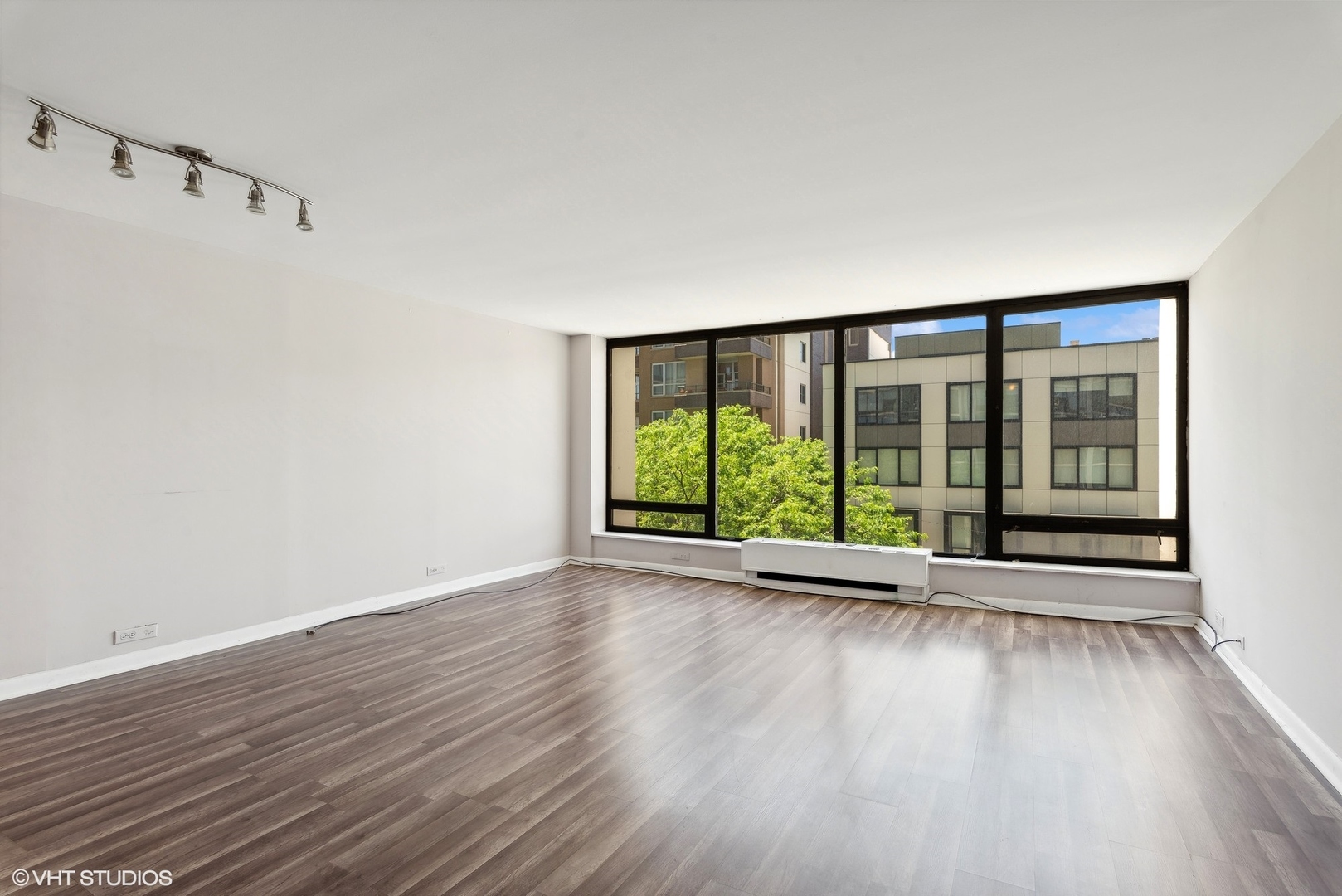 5445 North Sheridan Road, Unit 403 Chicago, IL 60640 - Photo 2 of 11 a view of an empty room with wooden floor and a window