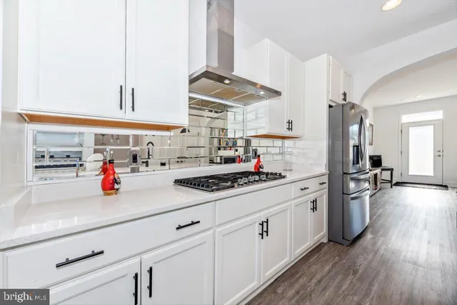 a kitchen with stainless steel appliances a stove and wooden floor