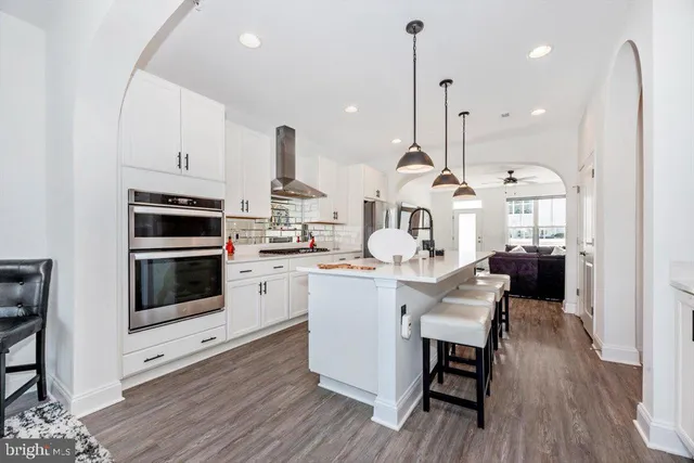 a kitchen with stainless steel appliances kitchen island granite countertop a stove a sink and a wooden floors