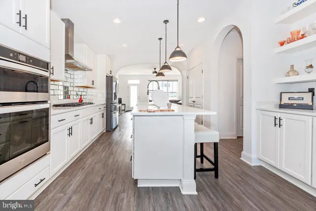 a kitchen with stainless steel appliances granite countertop a stove a sink dishwasher and a refrigerator with wooden floor