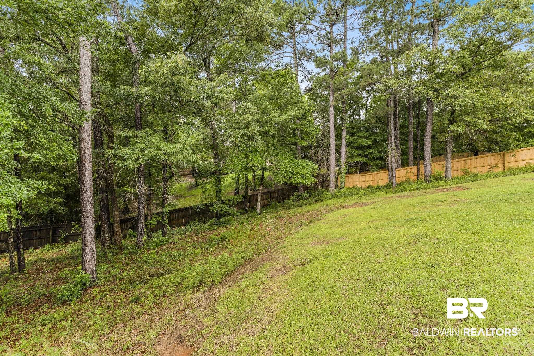 35814 Delvan Lane Bay Minette, AL 36507 - Photo 49 of 53 Spacious outdoor area featuring a sloped grassy lawn, mature trees, and a wood privacy fence