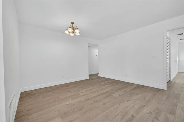 an empty room with wooden floor and fan