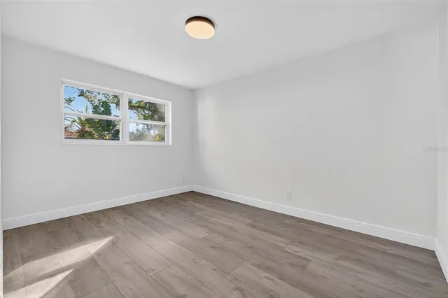 an empty room with wooden floor and window