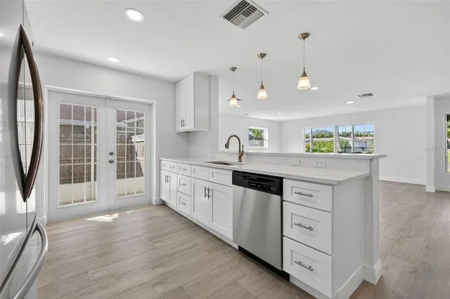 a large white kitchen with granite countertop a large counter top and sink