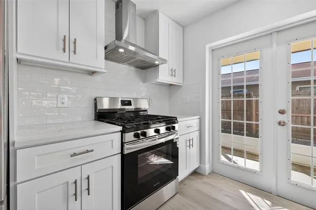 a kitchen with stainless steel appliances granite countertop white cabinets and a stove top oven