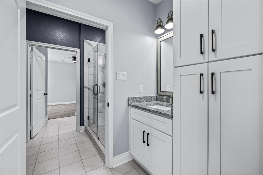 1701 Belzise Terrace Fort Worth, TX 76104 - Photo 12 of 35 a bathroom with a granite countertop sink a mirror and a shower