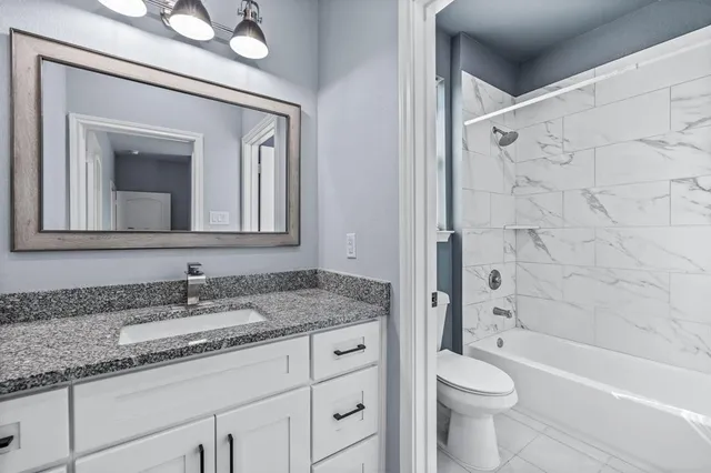a bathroom with a granite countertop toilet a sink and a bathtub