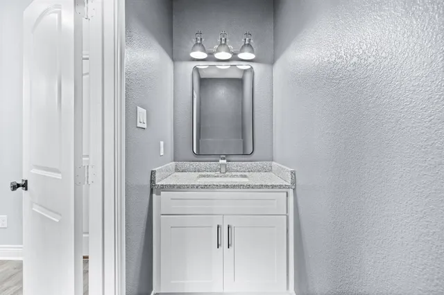 a bathroom with a granite countertop sink a mirror and a vanity