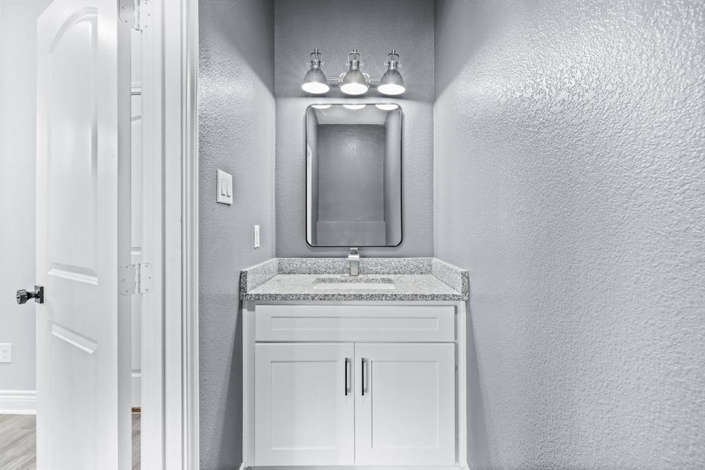 1701 Belzise Terrace Fort Worth, TX 76104 - Photo 17 of 35 a bathroom with a granite countertop sink a mirror and a vanity