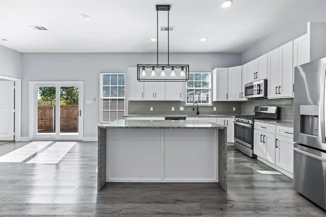 a kitchen with stainless steel appliances granite countertop a stove a sink and white cabinets