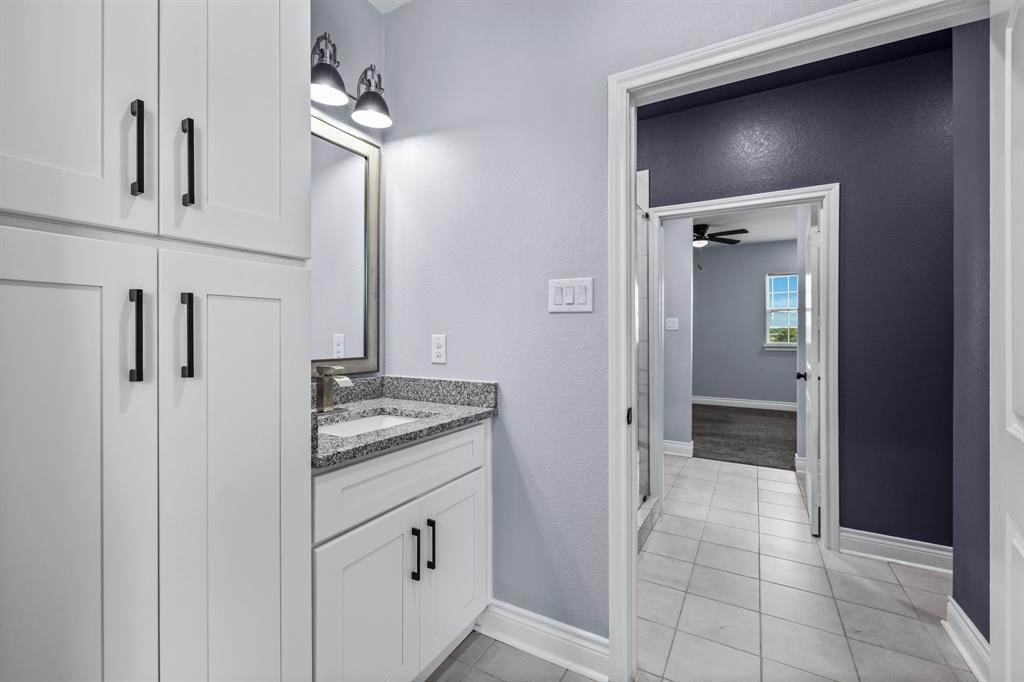 1701 Belzise Terrace Fort Worth, TX 76104 - Photo 24 of 35 a bathroom with a granite countertop sink a mirror and a vanity