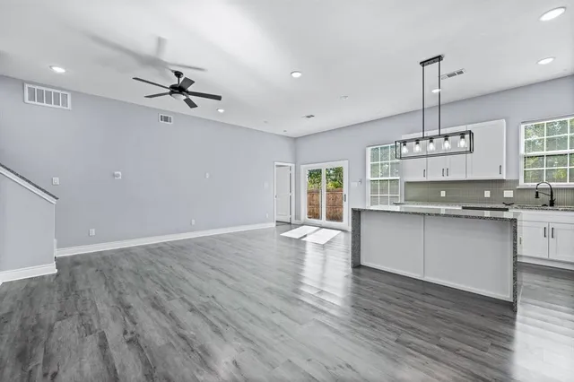 a kitchen with kitchen island granite countertop a sink cabinets and wooden floor