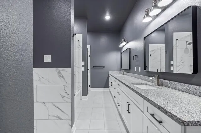 a spacious bathroom with a granite countertop sink a mirror and shower