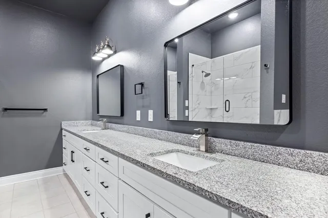 a bathroom with a granite countertop double vanity sink and a mirror