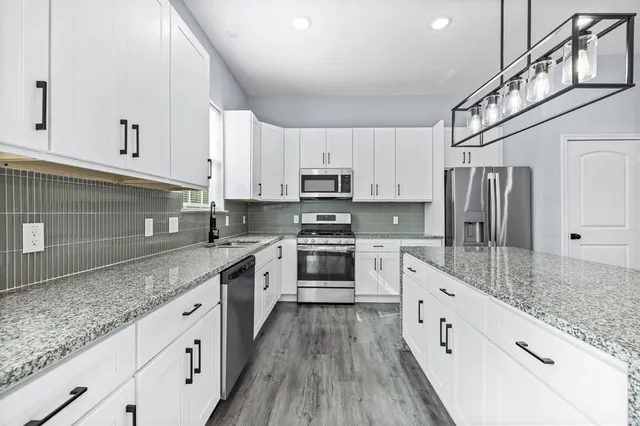 a kitchen with stainless steel appliances granite countertop a stove a sink and a refrigerator