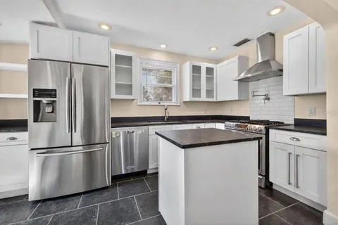 a kitchen with stainless steel appliances granite countertop a refrigerator a sink and a stove