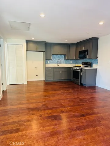 a view of kitchen with kitchen island a sink wooden floor and living room view