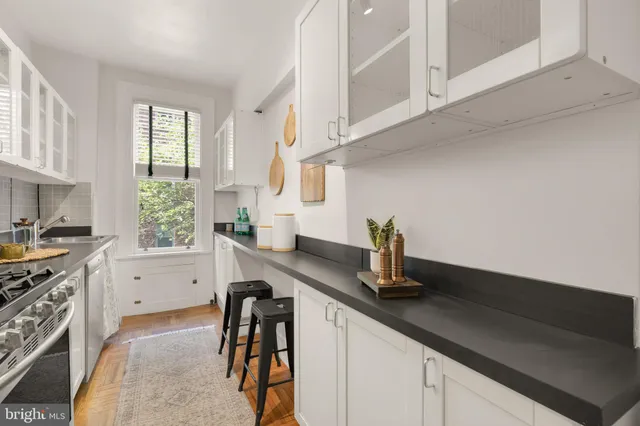 a kitchen with stainless steel appliances a sink a stove and white cabinets next to a window