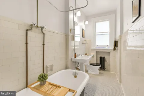 a bathroom with a tub sink vanity granite and toilet