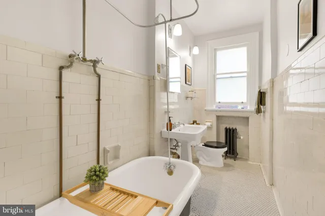 a bathroom with a tub sink vanity granite and toilet