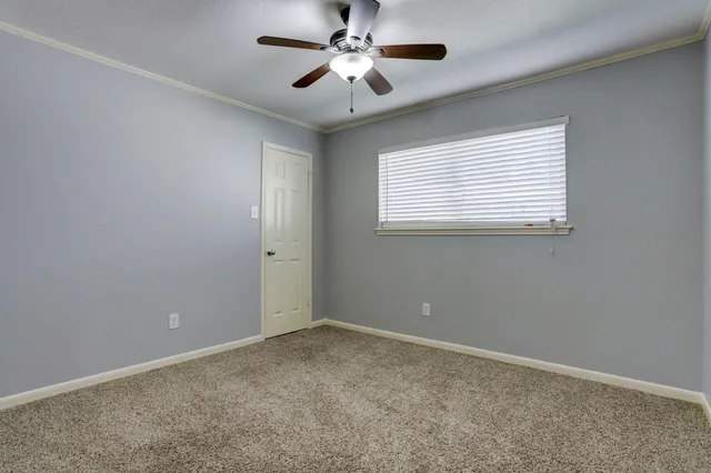 an empty room with a window and a fan