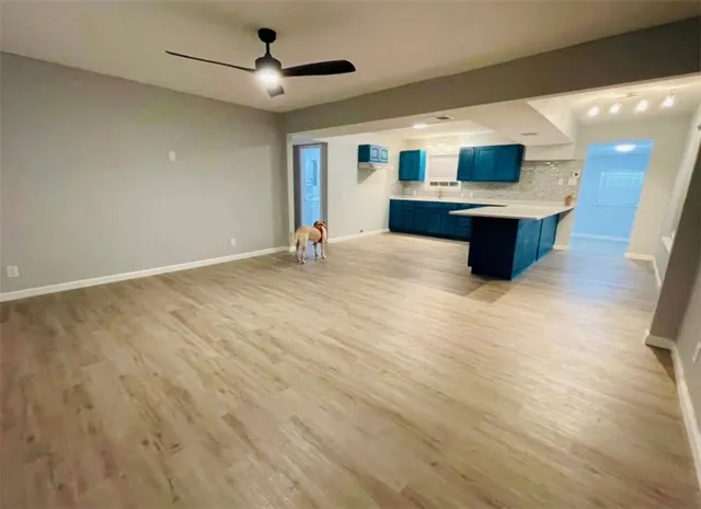 a large kitchen with stainless steel appliances a large counter top and wooden floor