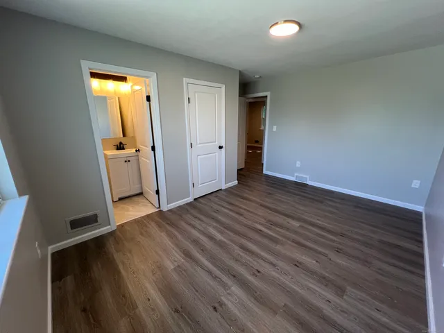 an empty room with wooden floor and entrance