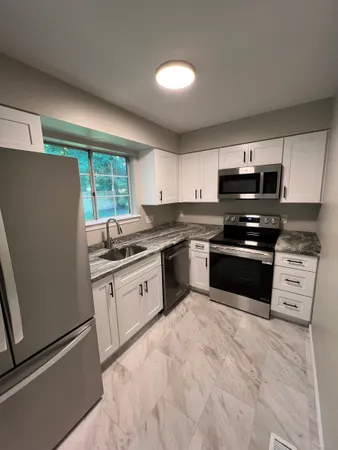a kitchen with granite countertop a refrigerator sink and cabinets