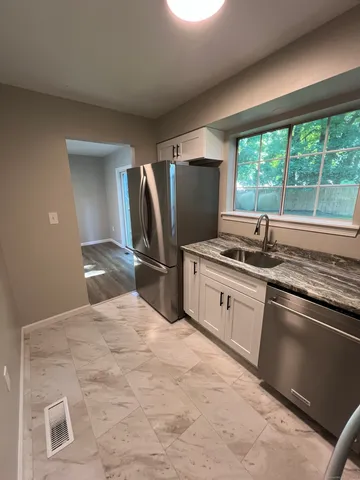 a kitchen with stainless steel appliances kitchen island granite countertop a sink stove and refrigerator