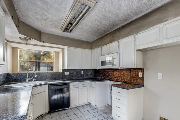 a kitchen with granite countertop a sink stove and cabinets