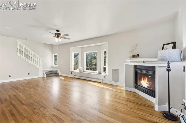 a view of an empty room with wooden floor fireplace and a window