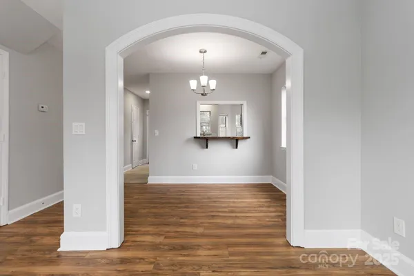 a view of a hallway with wooden floor and a chandelier