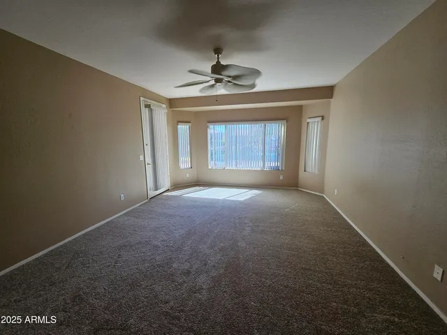 en empty room with windows and ceiling fan