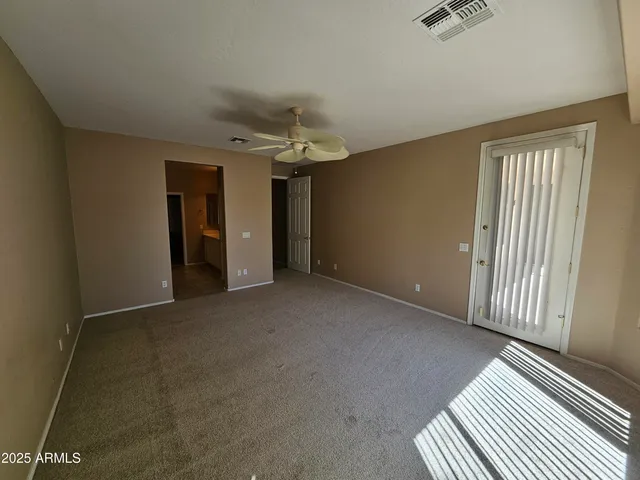 an empty room with chandelier fan and windows