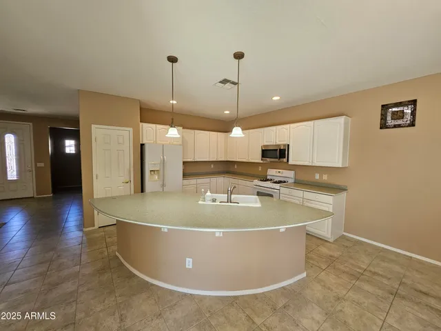 a view of a kitchen with stainless steel appliances granite countertop a sink a oven a dining table and chairs