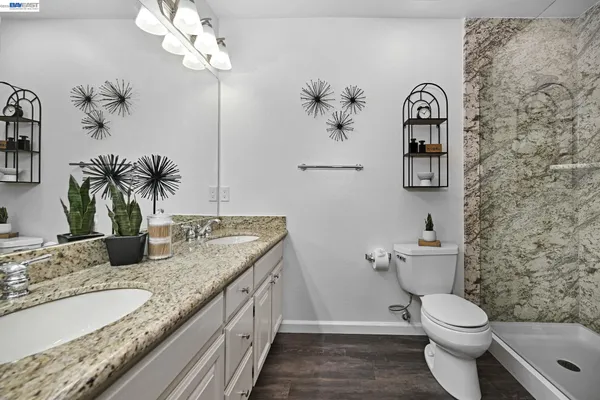 a bathroom with a granite countertop toilet sink and mirror