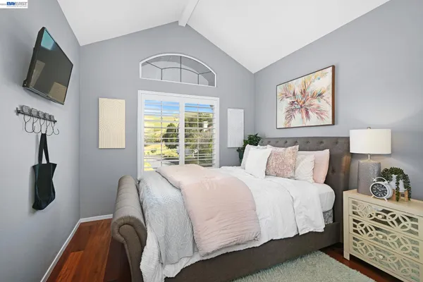 a bedroom with a bed a mirror and a flat tv screen on a dresser