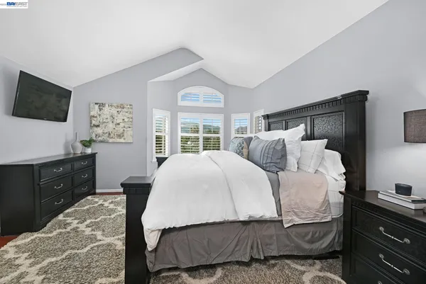 a bedroom with a large bed and a flat tv screen on dresser